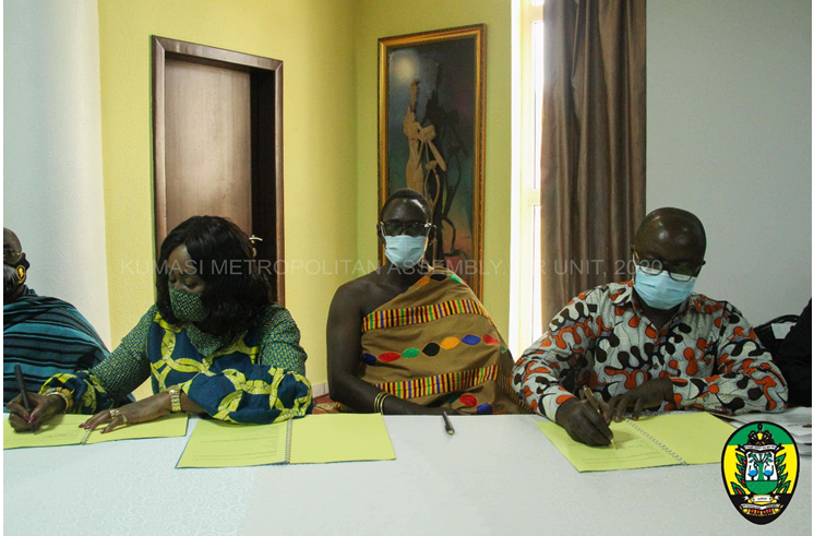 Hon. Barbara Gyasi and Kumasi Mayor, Hon. Osei Assibey Antwi signing the document while Oheneba Owusu Afriyie IV, Otumfour’s Apagyahene (middle) looks on.
